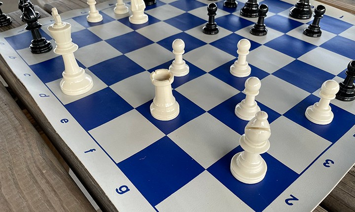 Black and white chess pieces on a blue and white checkered board.
